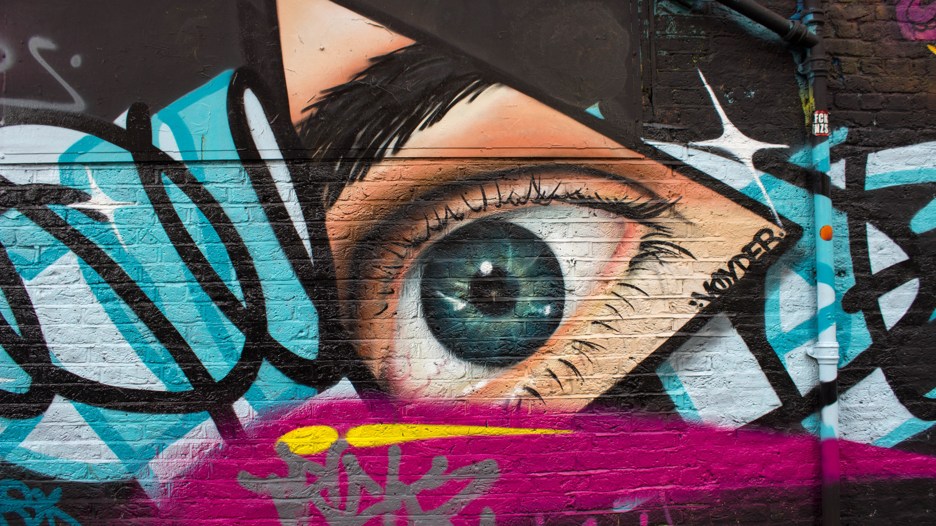 graffiti wall featuring a large blue eye in a triangle