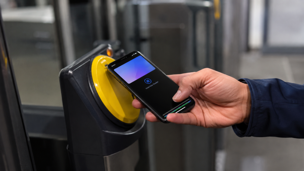 Close-up of a smartphone being tapped against a Tube ticket barrier reader to pay a capped fare.