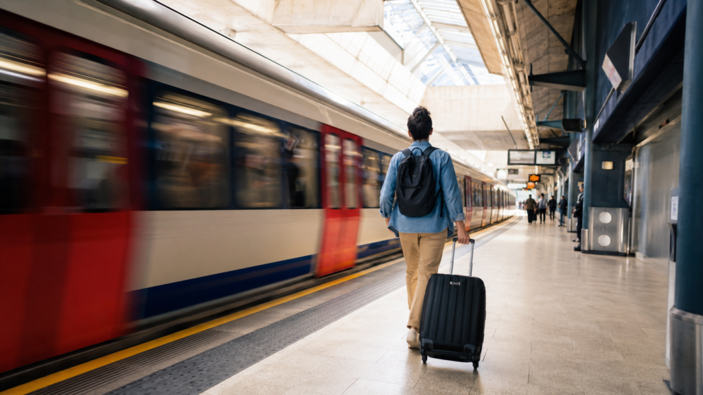 Traveller with a suitcase on a bright airport Underground platform as a train arrives.